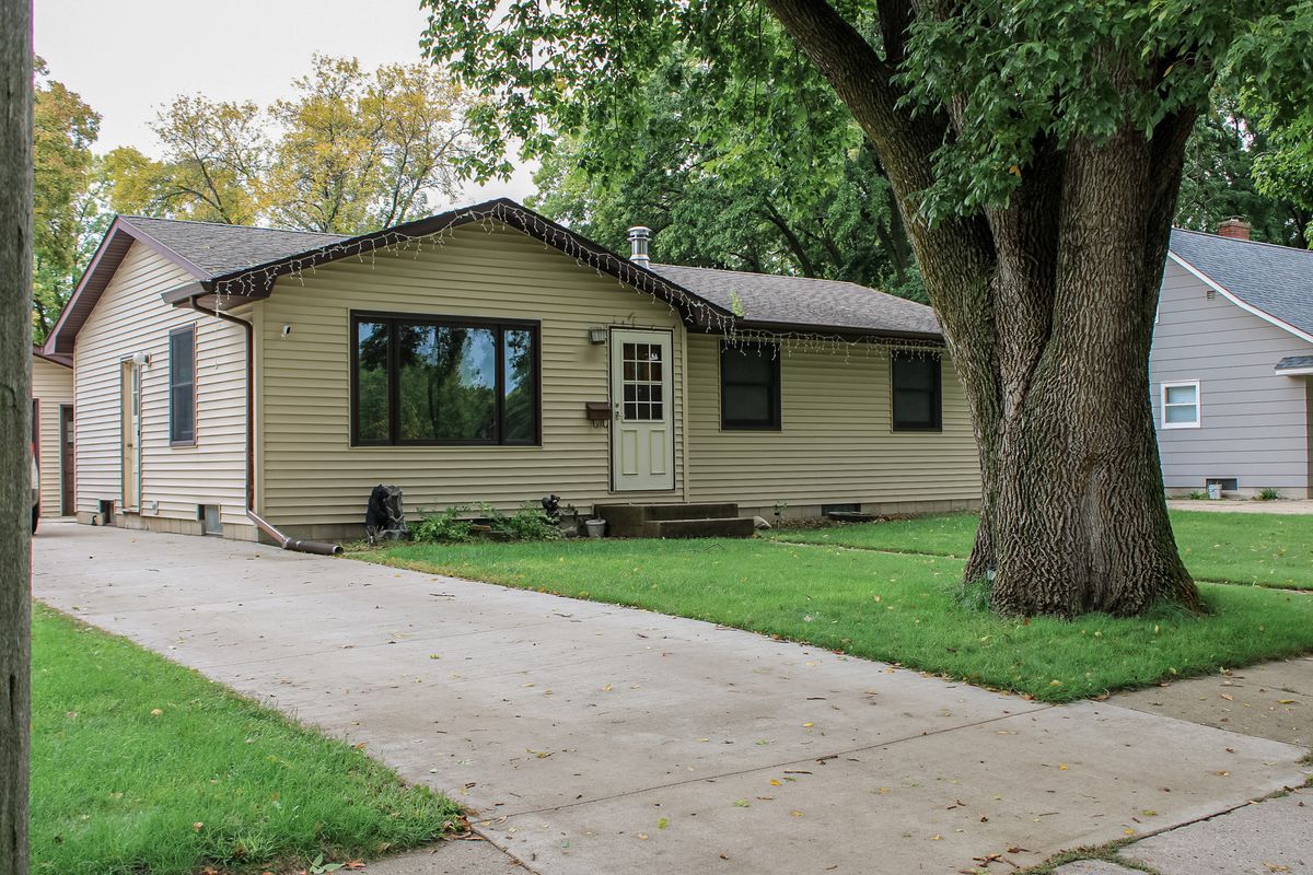 Tan ranch home with mature tree and driveway